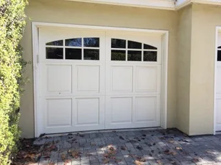 Single-car white carriage-style garage door with arched windows on stucco house