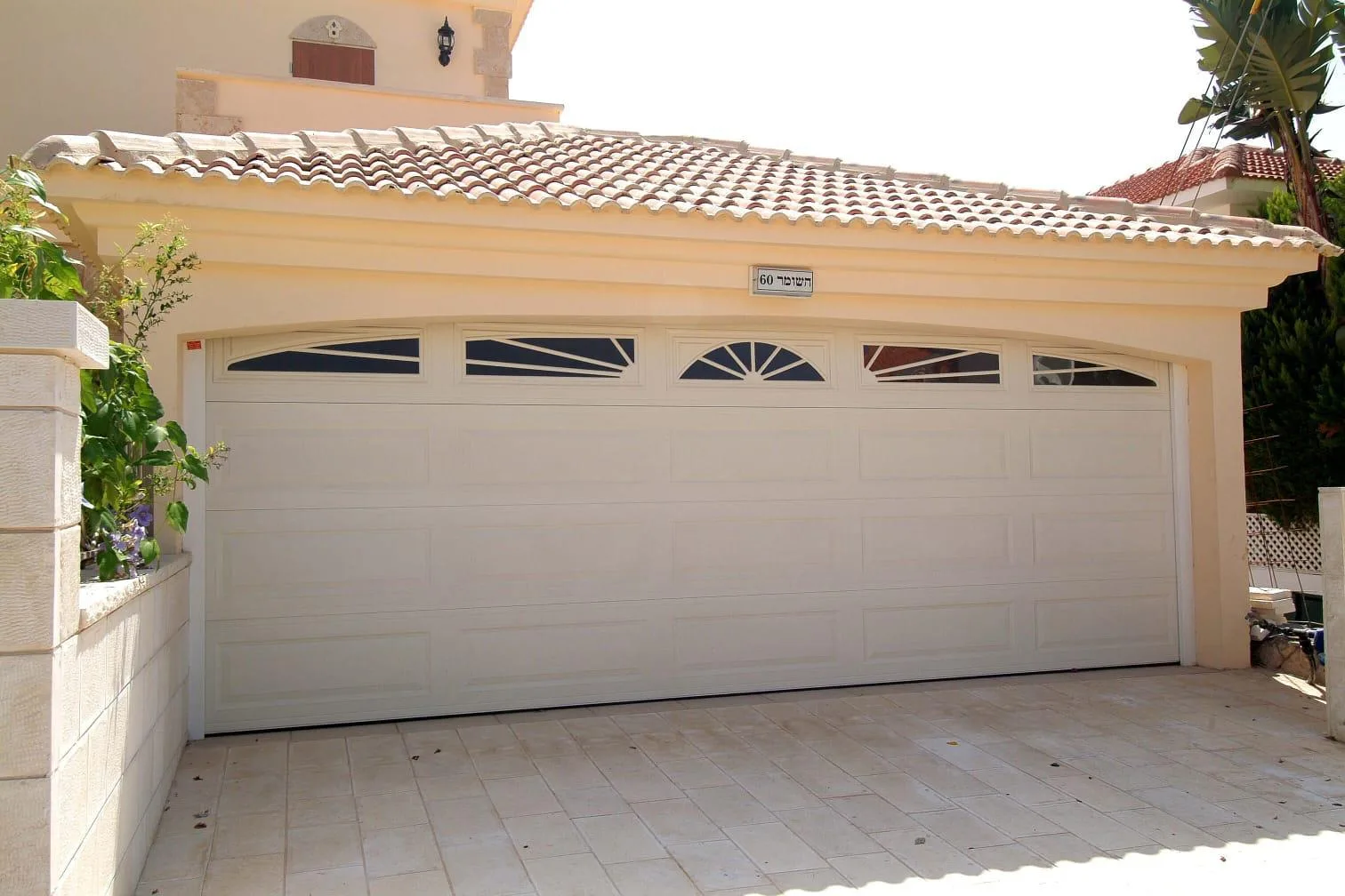 Cream raised-panel garage door with decorative sunburst windows