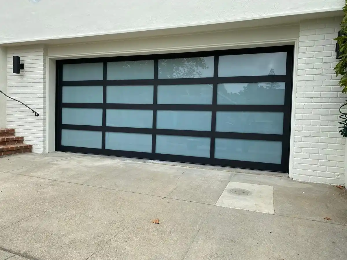 Full-view frosted glass garage door on white brick home