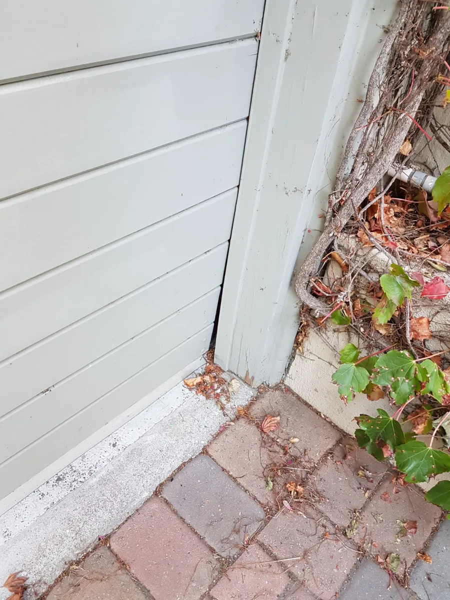 Close-up of garage door bottom corner showing rust and deterioration