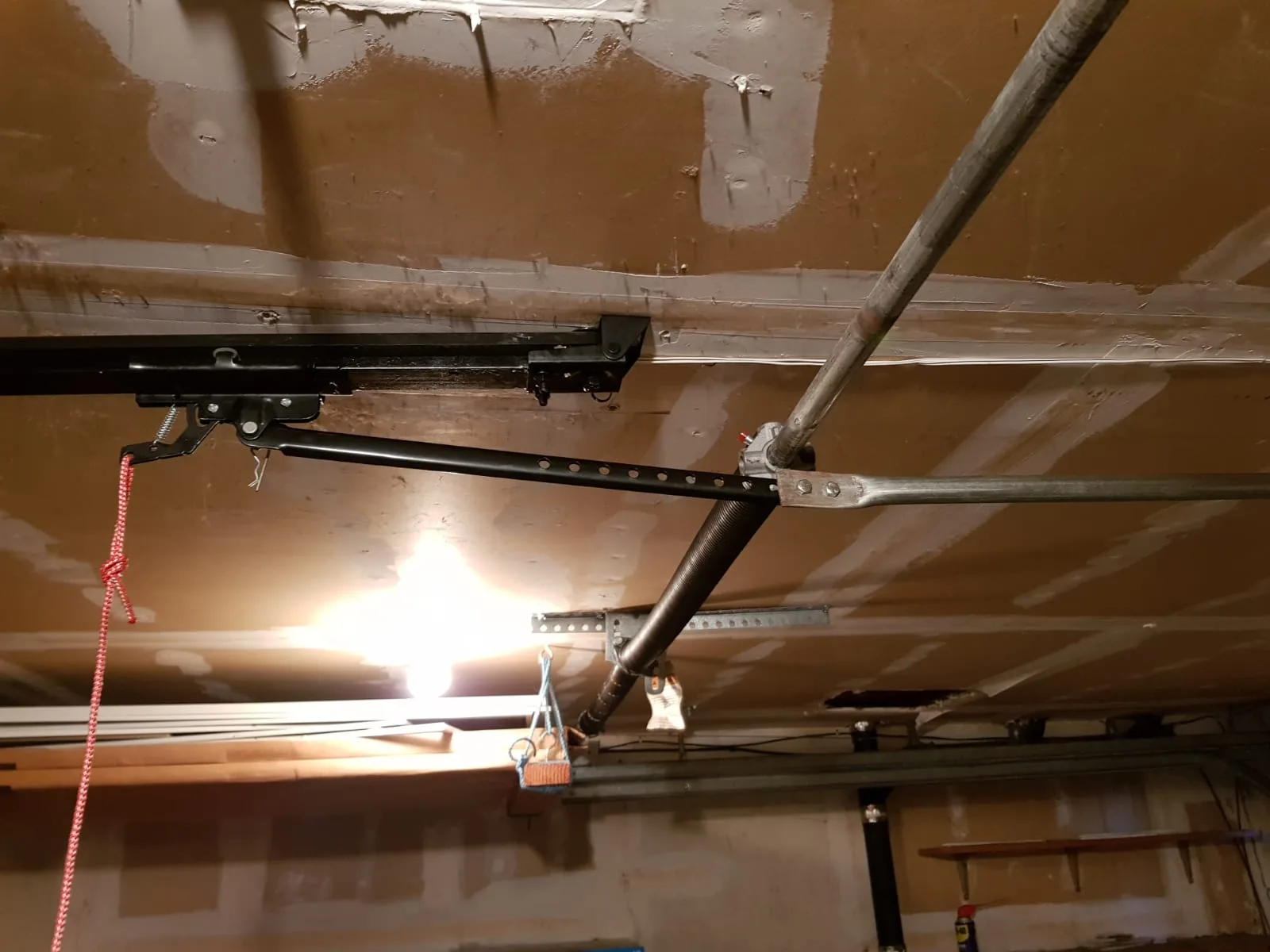 Interior view of garage door spring system, track, and opener hardware