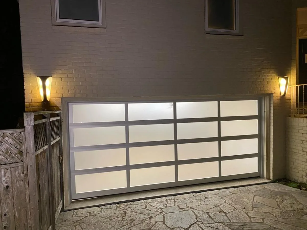 Frosted glass garage door illuminated at night with silver frame