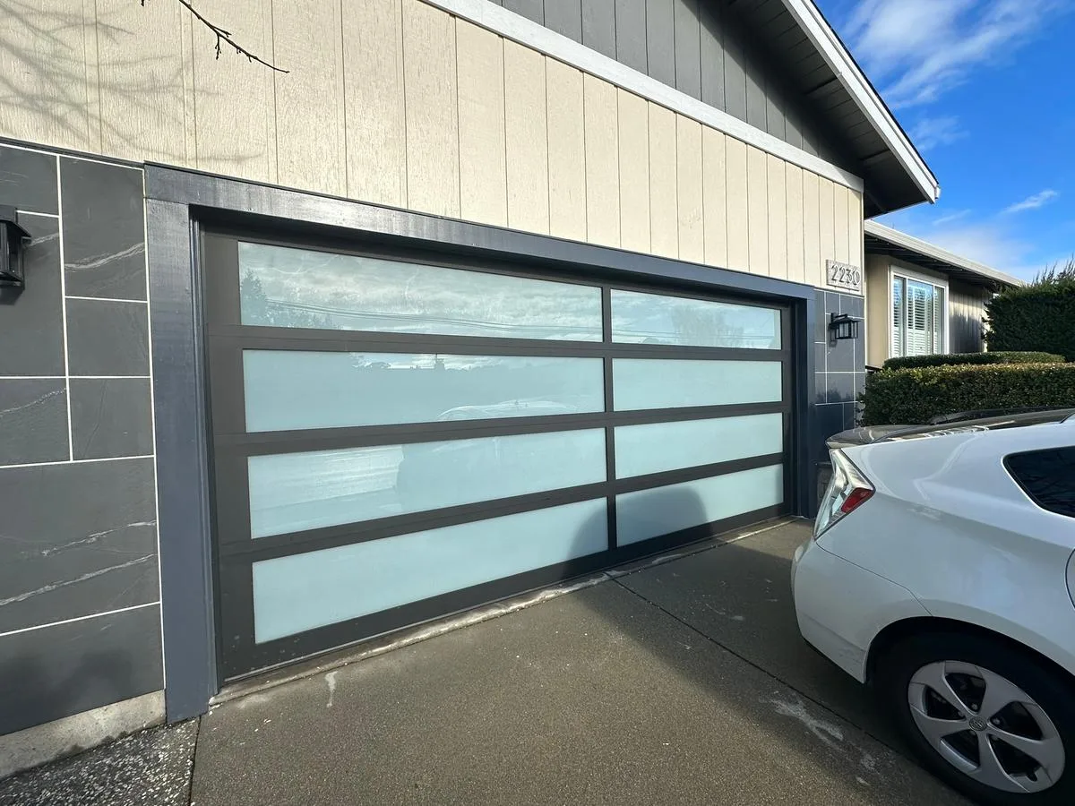 Contemporary glass garage door on home with stone accent wall