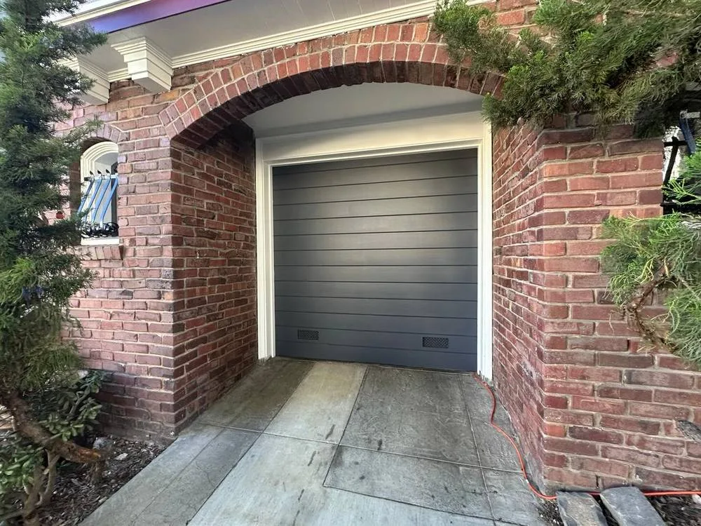 Gray flush panel garage door in brick archway