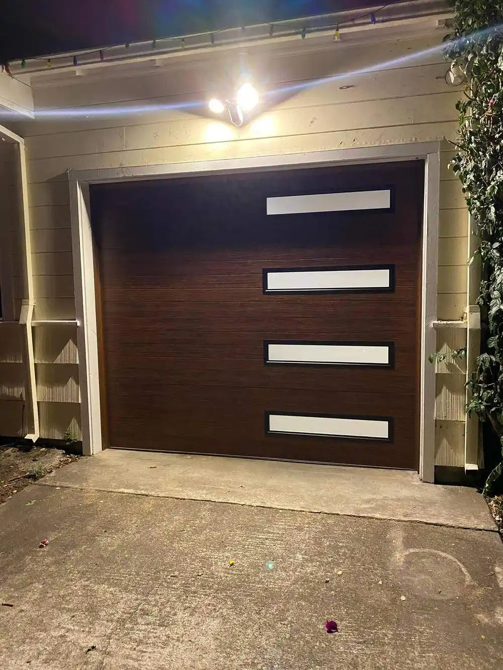 Modern wood-look garage door with horizontal windows at night