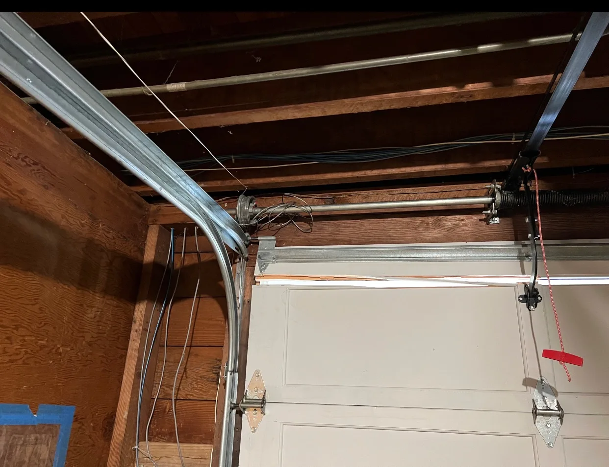 Torsion spring, cables, drums, and curved track at top of garage door