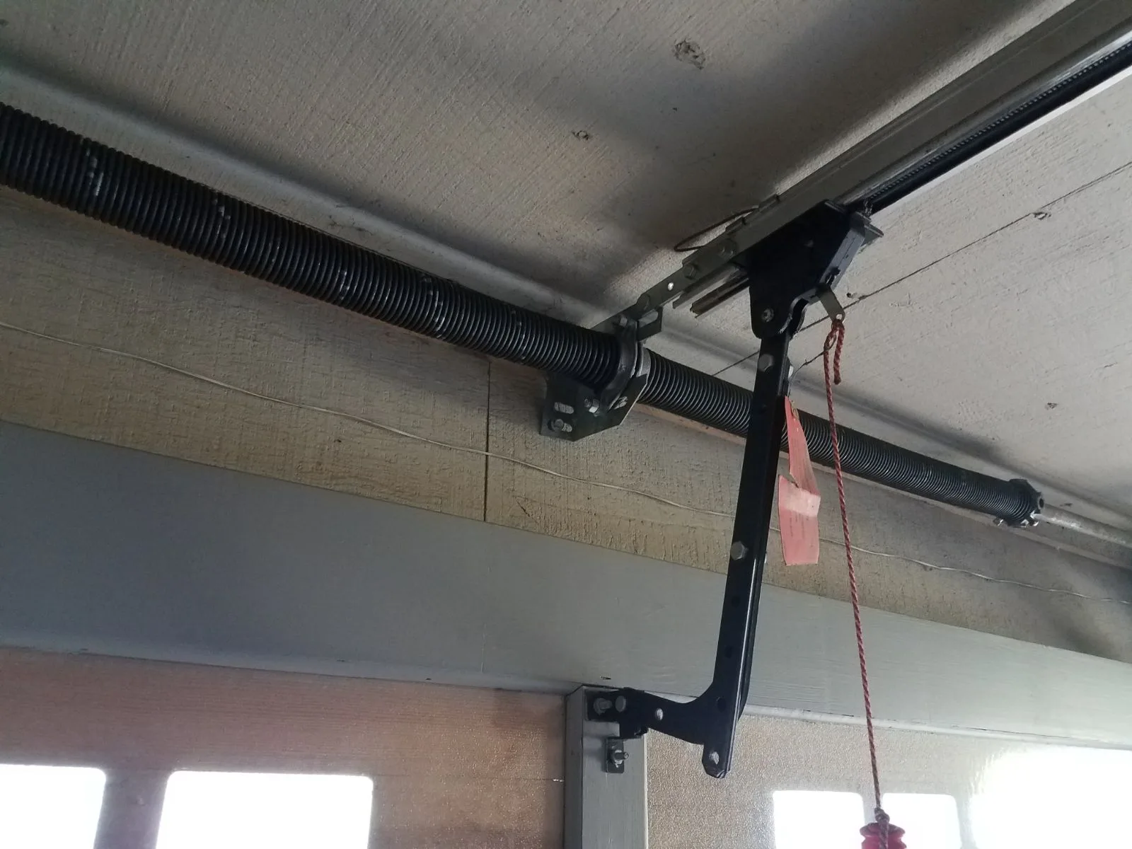 Close-up of garage door torsion spring and hardware mounted on ceiling
