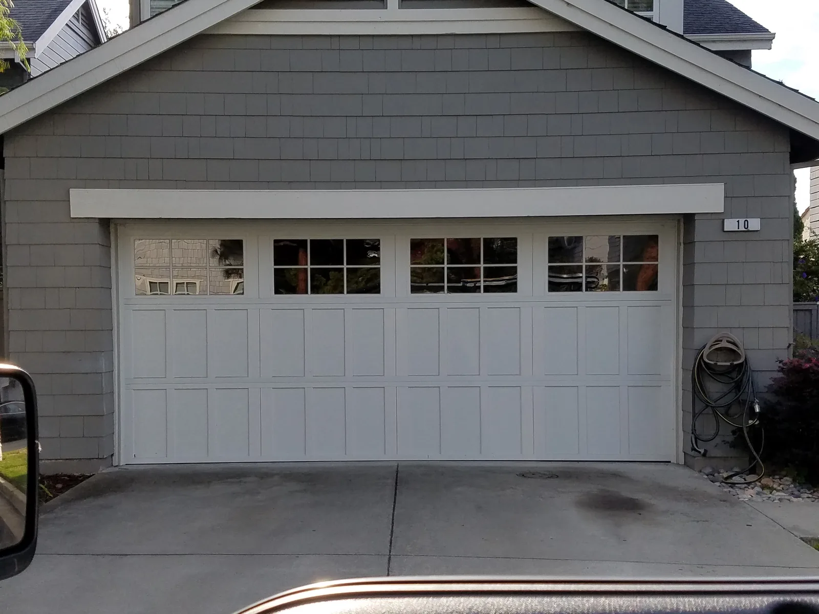 White carriage-style garage door with windows on a gray shingled house